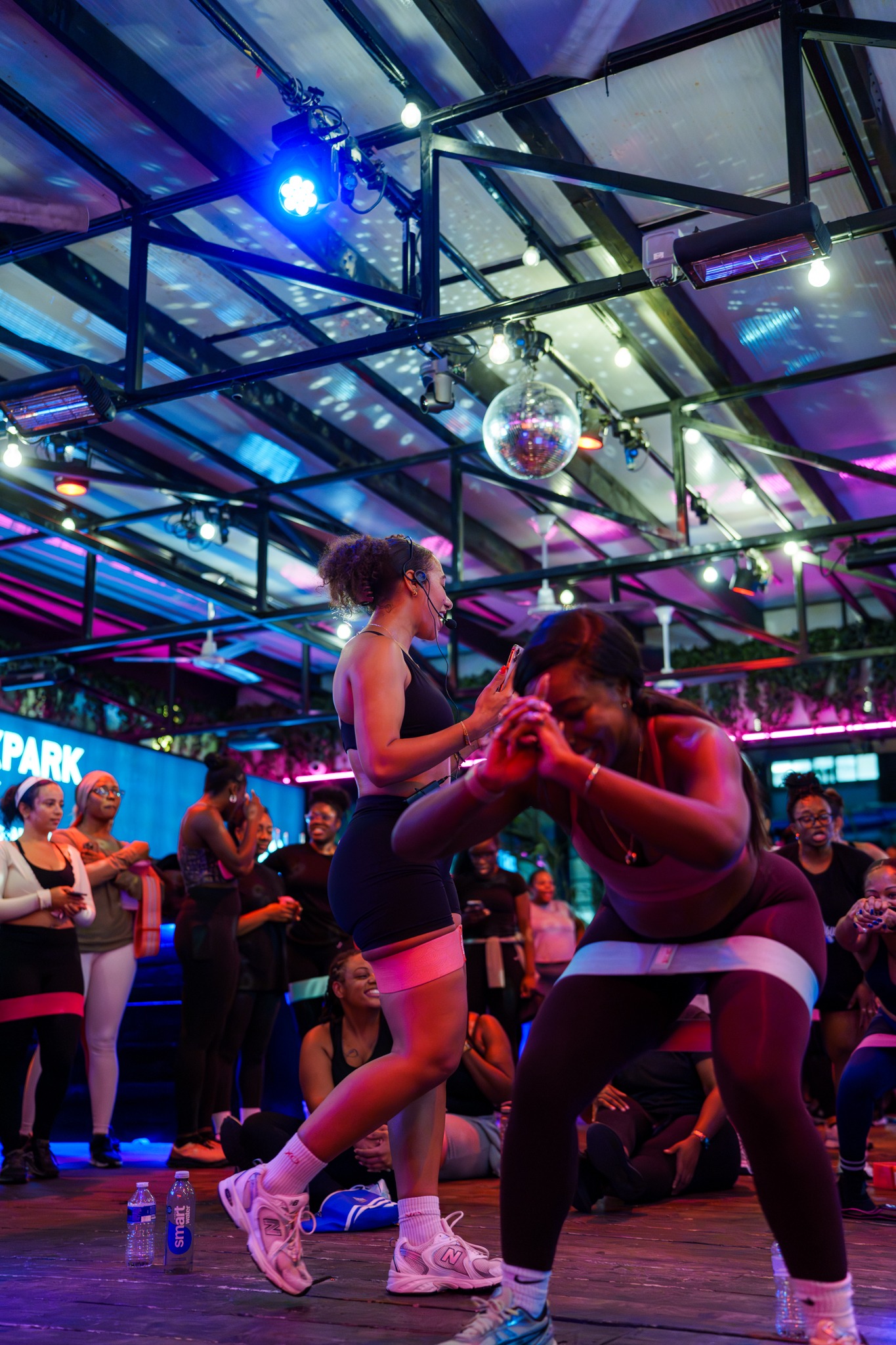 Christina leading a lively community resistance-band workout under colourful lights